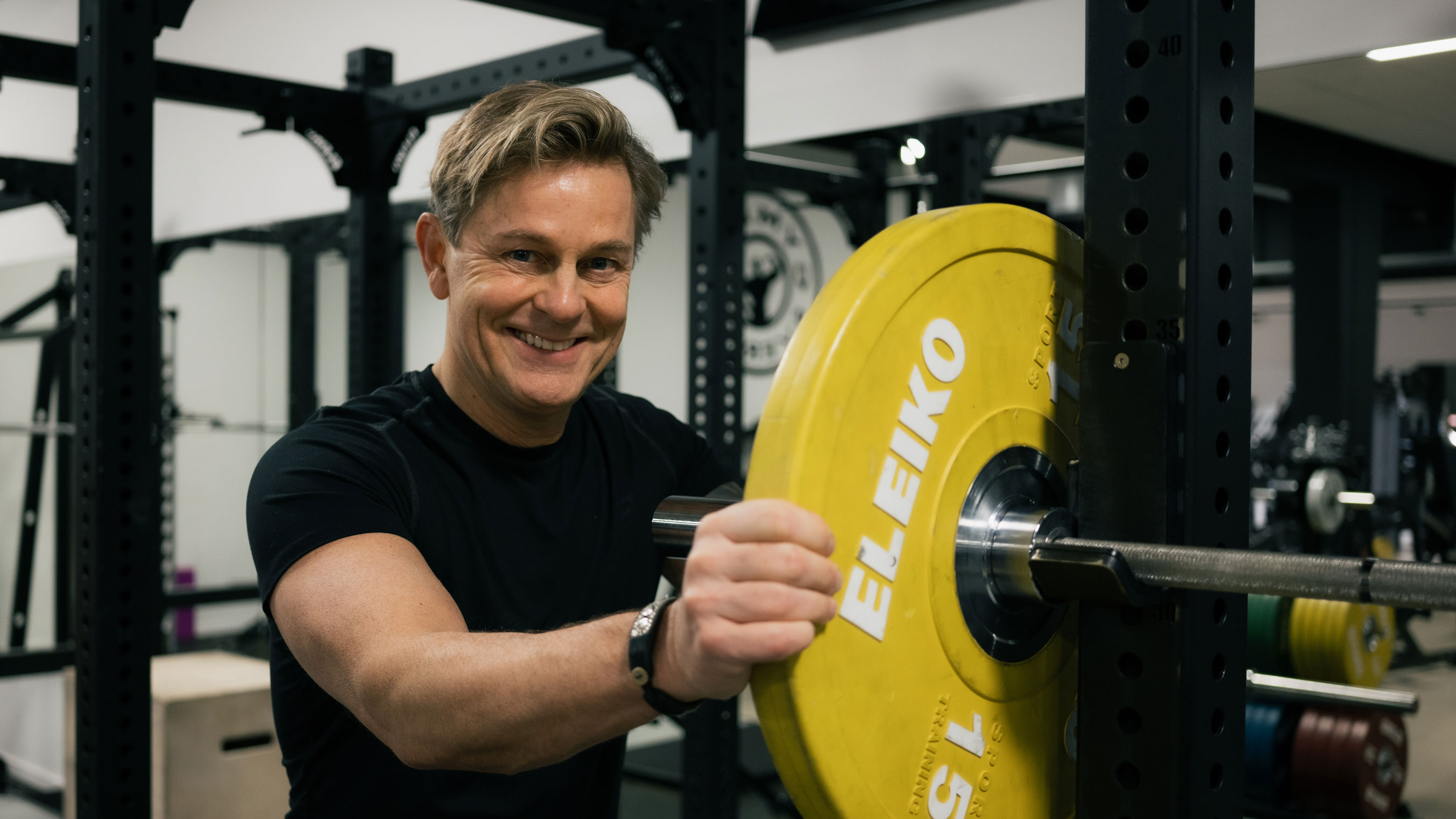 Niklas Wahlgren placing a weight on a bar in gym setting